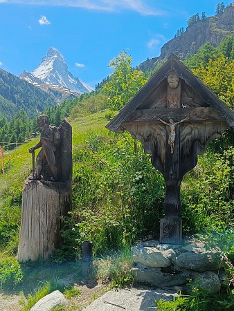 Dřevěné sochy umístěné v horské přírodě s výrazným zasněženým vrcholem