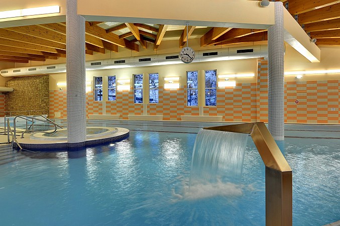 Moderní krytý bazén s teplým osvětlením a dřevěným stropem