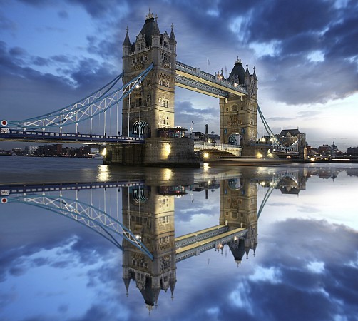 Tower Bridge osvětlený večerními světly se odráží v klidné vodní hladině