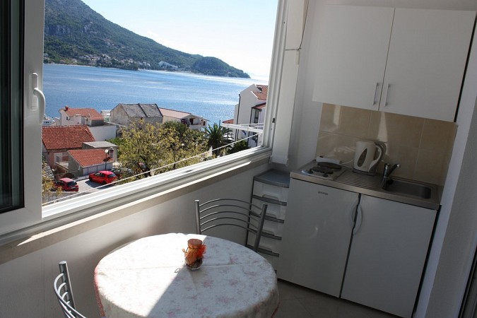 Balkón s kulatým stolem a kuchyňskou linkou, odkud je výhled na moře