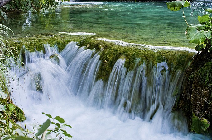 Vodopád s čistou vodou stéká přes mechem porostlou skalní hranu do spodního proudu