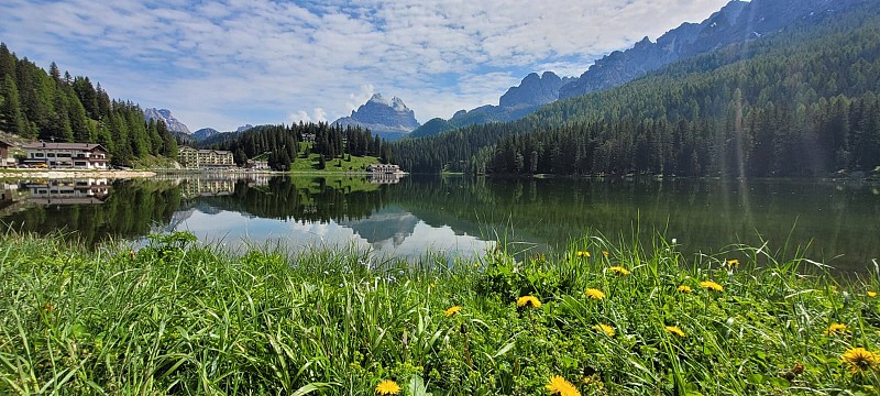 Horské jezero obklopené lesy a horami, které se zrcadlí v jeho klidné hladině