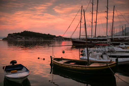 Přístav v Makarské s loděmi kotvícími na klidné vodě při západu slunce zbarveného do oranžových a růžových odstínů