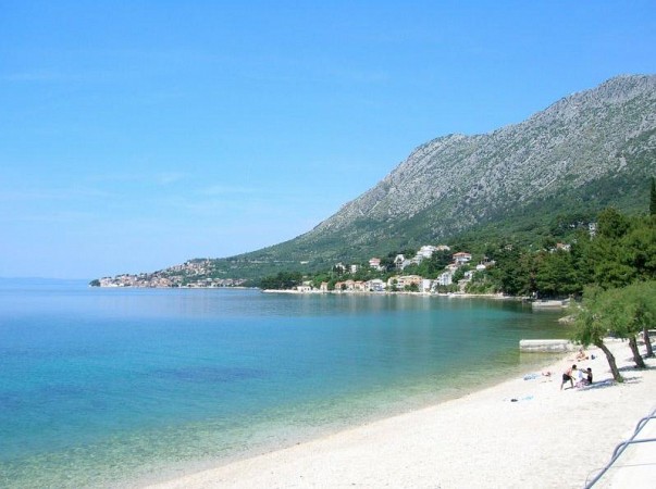 Oblázková pláž s lehátky u klidného moře