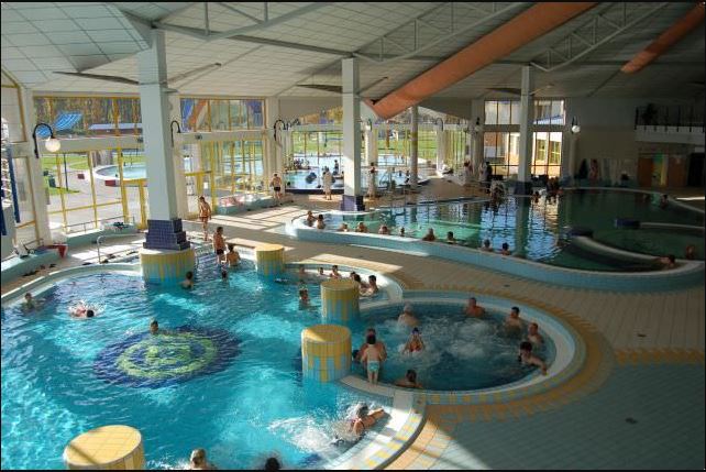 Vnitřní část termálních lázní s několika bazény a lidmi