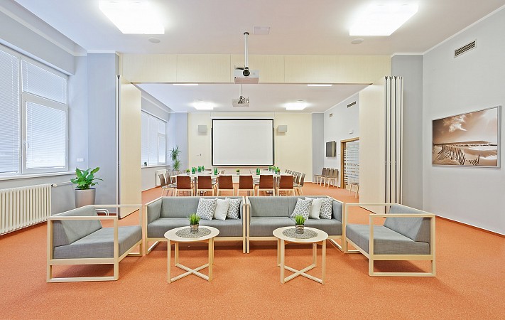 Prostorná konferenční místnost s promítacím plátnem, pohodlnými křesly a stolem