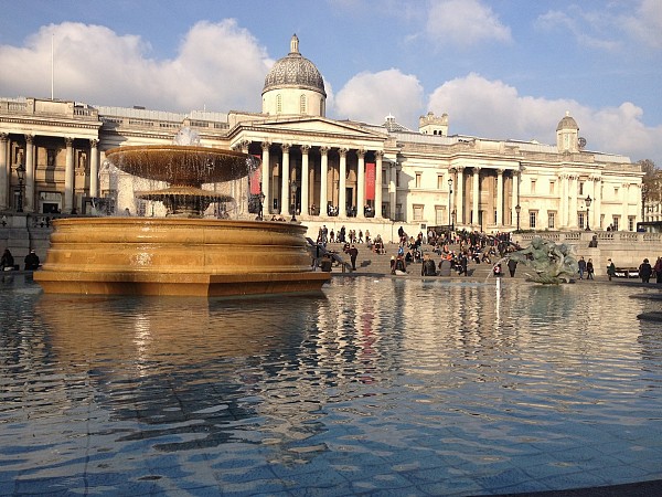 rafalgarské náměstí v Londýně zdobí velká fontána s vodní hladinou a za ní stojí budova Národní galerie