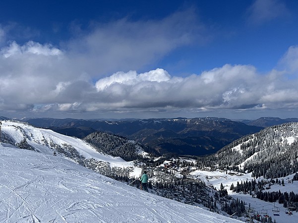 Zasněžený horský hřeben nabízí široký výhled do údolí a na vzdálené pohoří