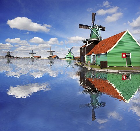 Nizozemsko, větrné mlýny a tradiční dřevěné domy v Zaanse Schans u vodní hladiny