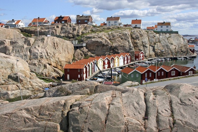 Přístavní městečko Smögen ve Švédsku s barevnými dřevěnými domky na skalnatém pobřeží a loděmi v přístavu