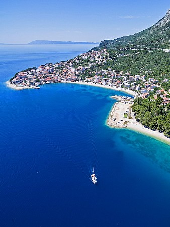 Pobřeží lemované zelenými kopci přechází do města s budovami podél břehu