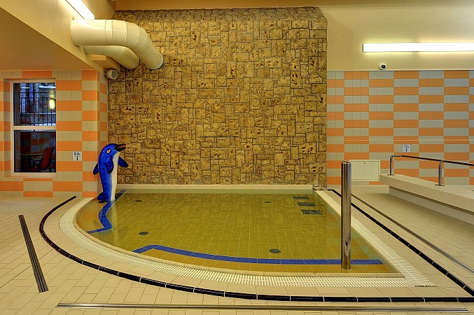 Menší termální bazén s minerální vodou v interiéru s kamennou stěnou