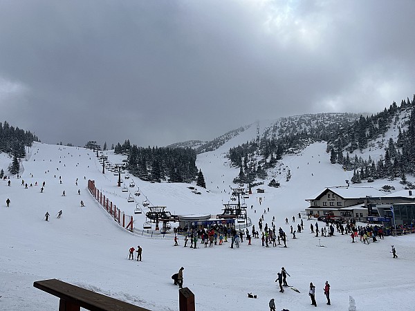 Lyžařské středisko s upravenými sjezdovkami, lanovkami a několika lyžaři na svahu