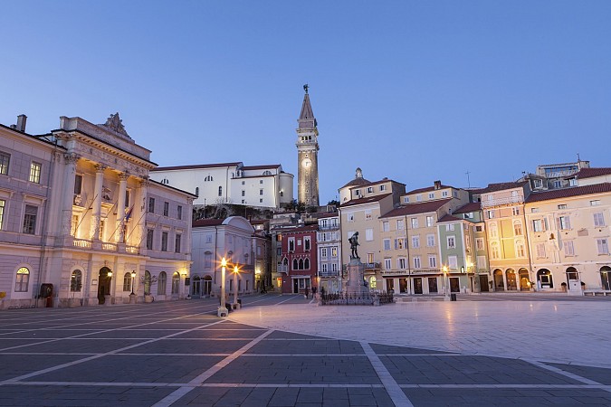 Večerní pohled na hlavní náměstí v Piraně se světly osvěcujícími historické budovy a kostelní věží