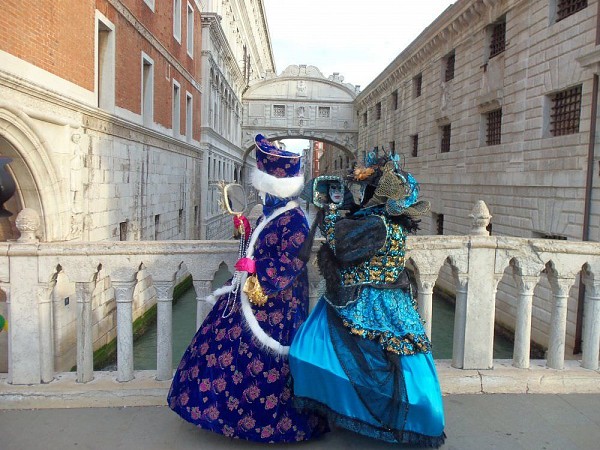 Dvě osoby v barevných karnevalových kostýmech a maskách