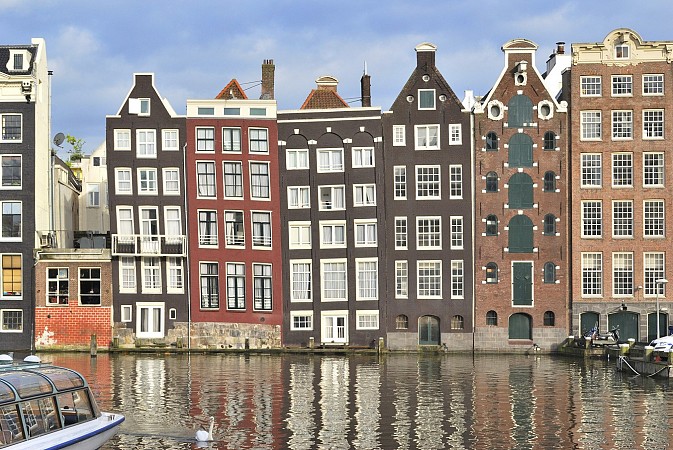Amsterdam, historické domy přezdívané Dancing Houses na nábřeží Damrak odrážející se ve vodě