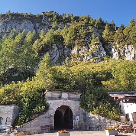 Kamenný vstup do podzemní štoly zasazený pod skalním masivem porostlým stromy