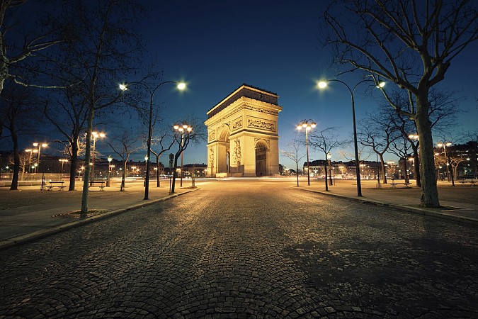 Osvětlený oblouk uprostřed širokého bulváru při večerním čase