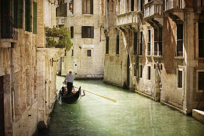 Úzký kanál v Benátkách s gondolou mezi historickými domy