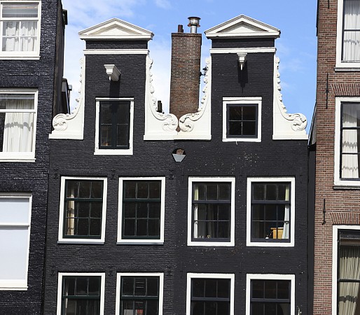 Tradiční úzké domy s typickými štíty v Amsterdamu, focené z ulice za denního světla