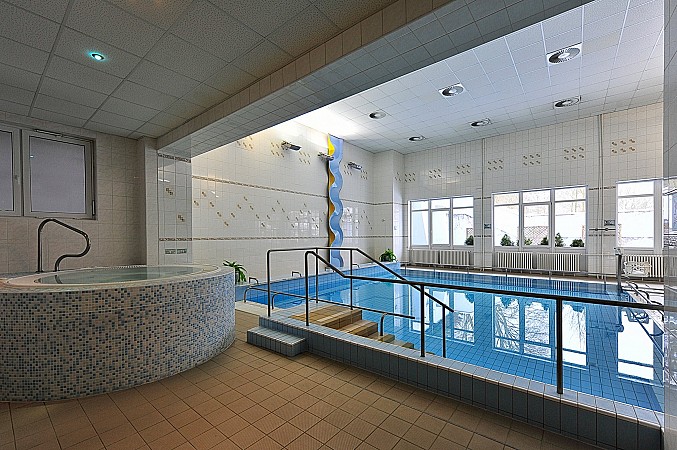 Vnitřní bazén s čistou modrou vodou, oddělenou vířivkou a velkými okny