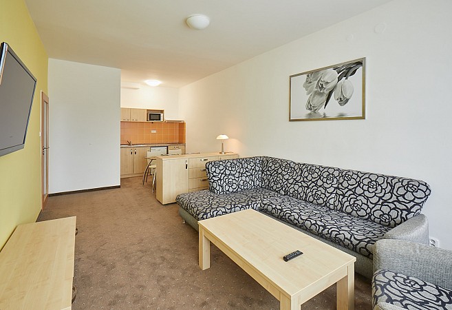 Útulný obývací pokoj s šedou rohovou sedačkou a dřevěným nábytkem