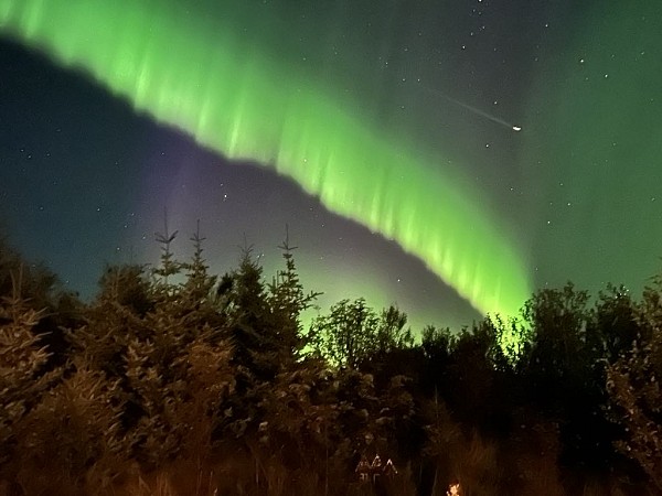 Zelené světelné pruhy polární záře na noční obloze