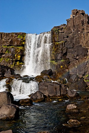 Vodopád stékající po skalní stěně do tmavé tůně