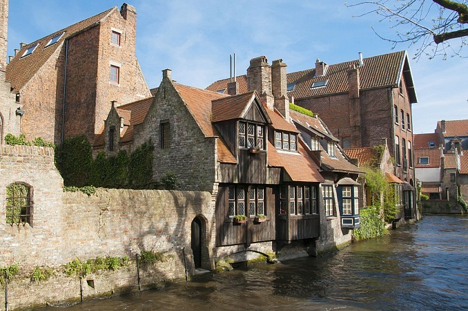 Nad kanálem se sklánějí staré cihlové domy se dřevěnými prvky a červenými střechami