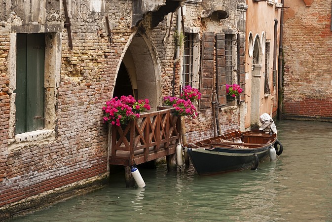 Gondola u historické budovy s květinami na balkóně
