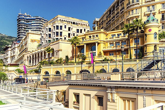 Barevné historické budovy s terasami a palmami stoupající po svahu