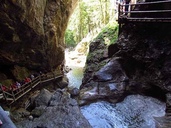 Úzký průchod mezi skalami s tekoucí vodou a dřevěnou lávkou