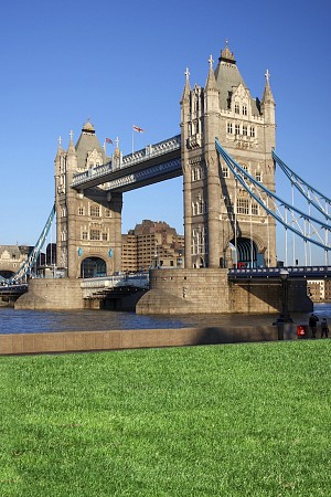 Tower Bridge v Londýně s dvěma kamennými věžemi a modrými visutými konstrukcemi pod jasnou modrou oblohou