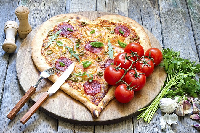 Pizza upečená do tvaru srdce, servírovaná na kulatém prkénku