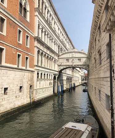 Uzavřený kamenný most spojující dvě historické budovy nad kanálem