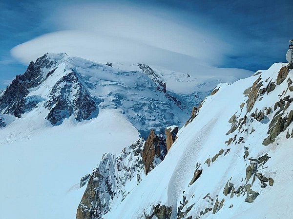 Sněhem pokrytý horský vrchol s ledovcem a oblakem usazeným nad špičkou