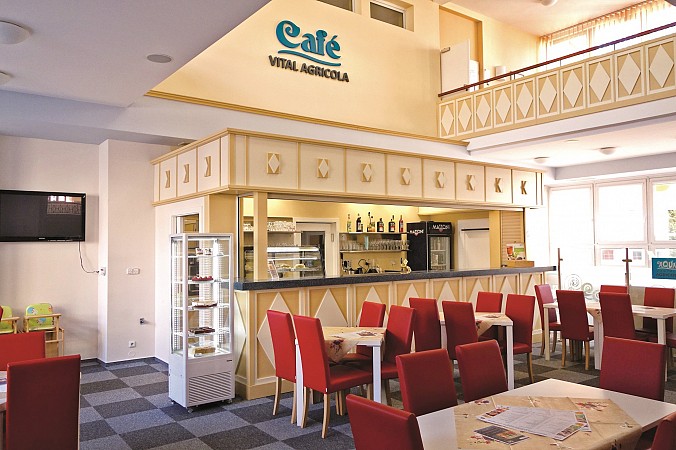 Stylová hotelová restaurace s červenými židlemi a dřevěným barem