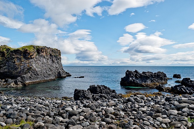 Pobřeží s černými kameny a lávovými útesy zasahujícími do moře